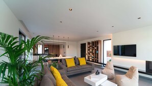 Een moderne woonkamer met een grijze bank, gele kussens, een witte salontafel en een beige loungestoel.