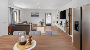 A modern living room with a sofa, a dining table with candles, and a large TV mounted on the wall. - Beautiful home in Bale (Bale)