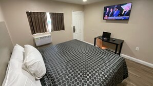 A hotel room with a bed, a desk, a television, and a window with curtains. - State Motel (South Gate)