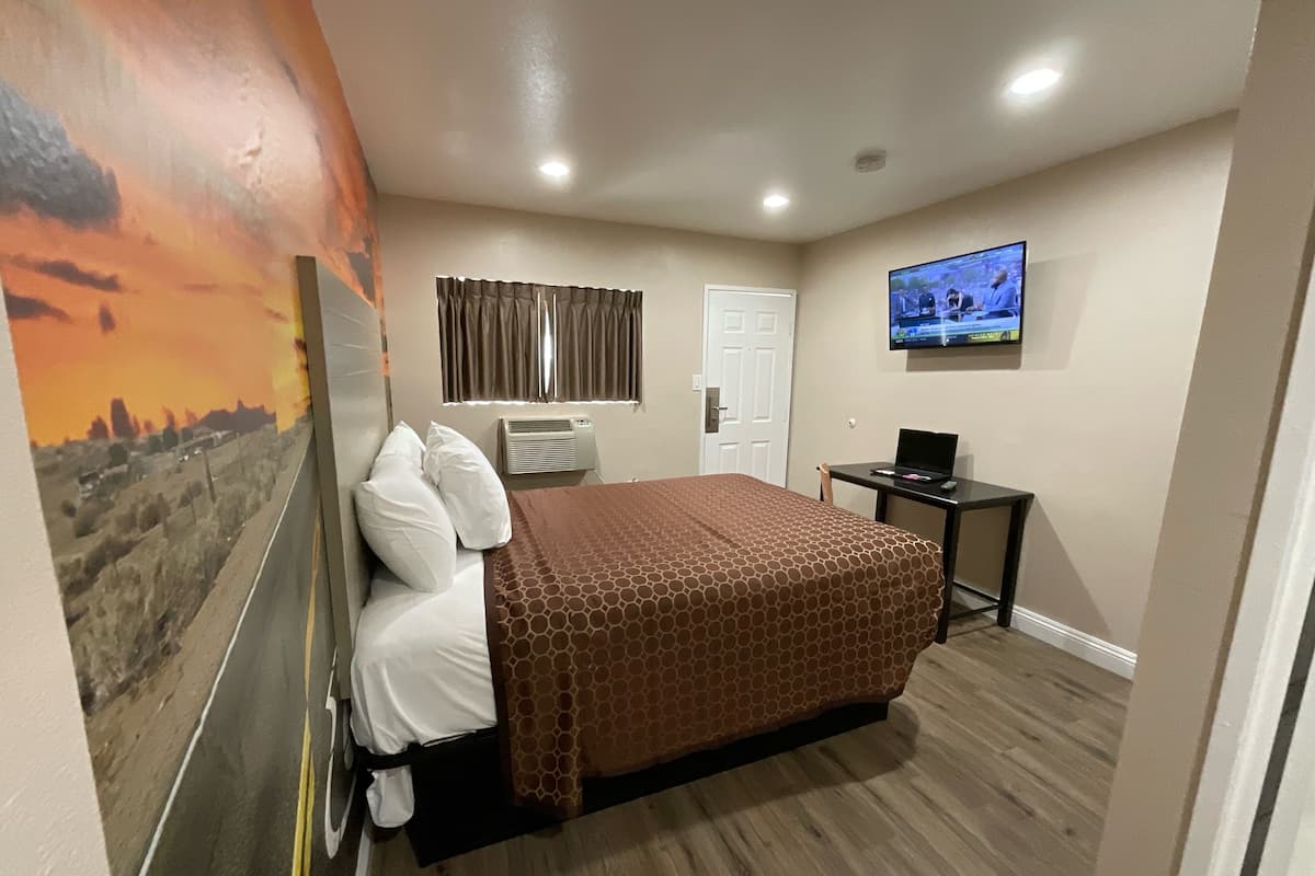 Ein Hotelzimmer mit einem Bett, einem Schreibtisch, einem Fernseher und einem Wandbild.