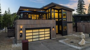 Una casa moderna de dos pisos con garaje, ventanas amplias y zona de estar exterior.