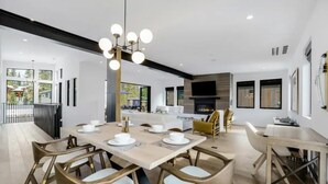 Un comedor moderno con una mesa grande, sillas y una lámpara de araña.