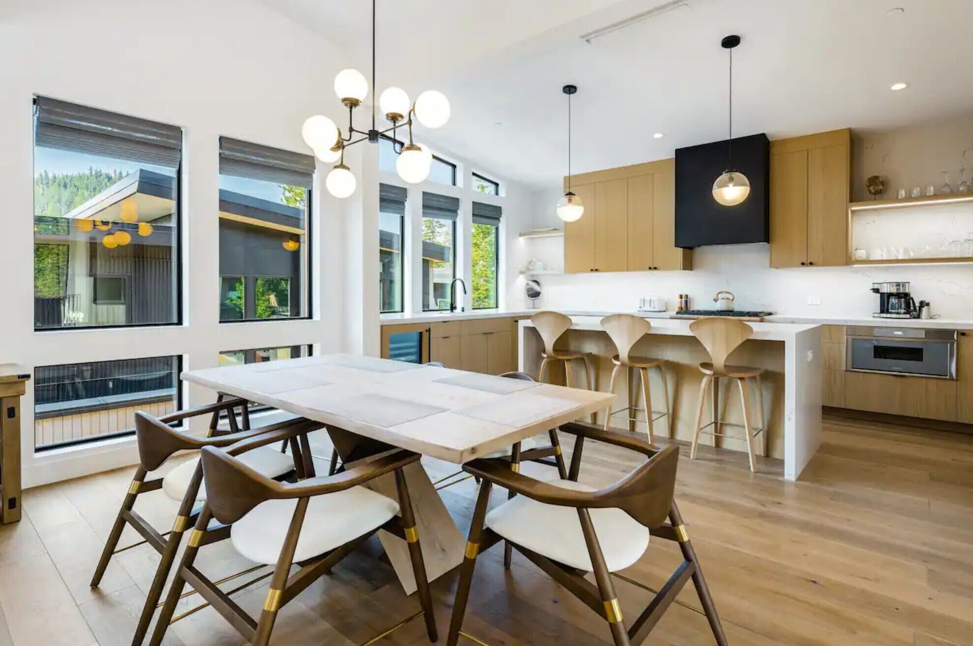 Una cocina moderna con una isla central, taburetes de bar e iluminación colgante.