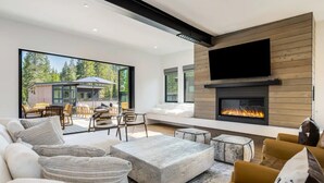 Una sala de estar moderna con chimenea, asientos cómodos y un gran ventanal con vista a una terraza.