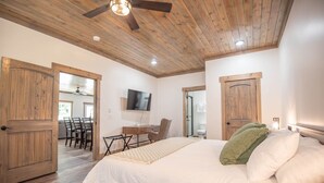A bedroom with a large bed, wooden ceiling, and a desk with a chair.
