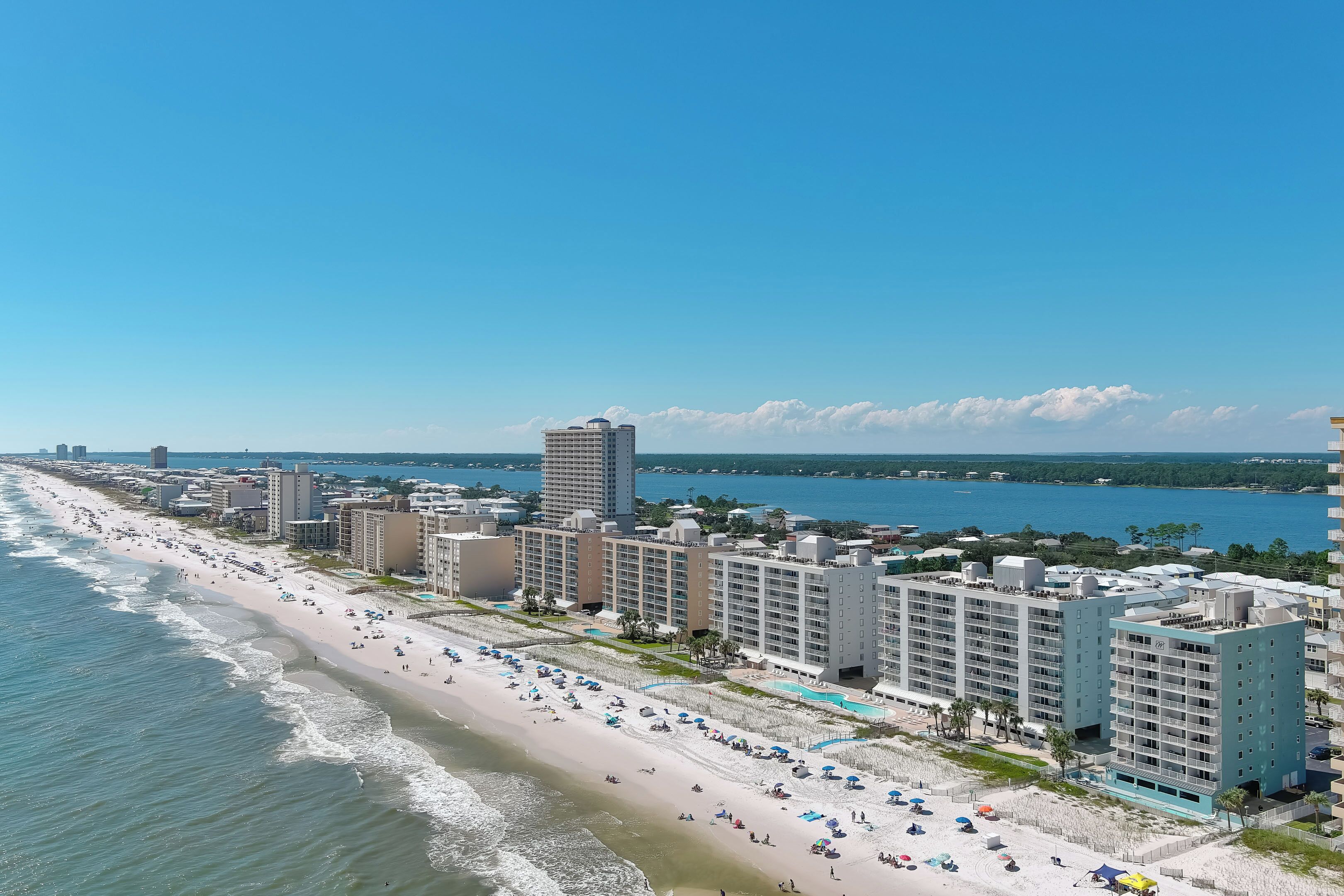 A beachfront hotel with multiple buildings, a sandy beach, and a clear view of the ocean.