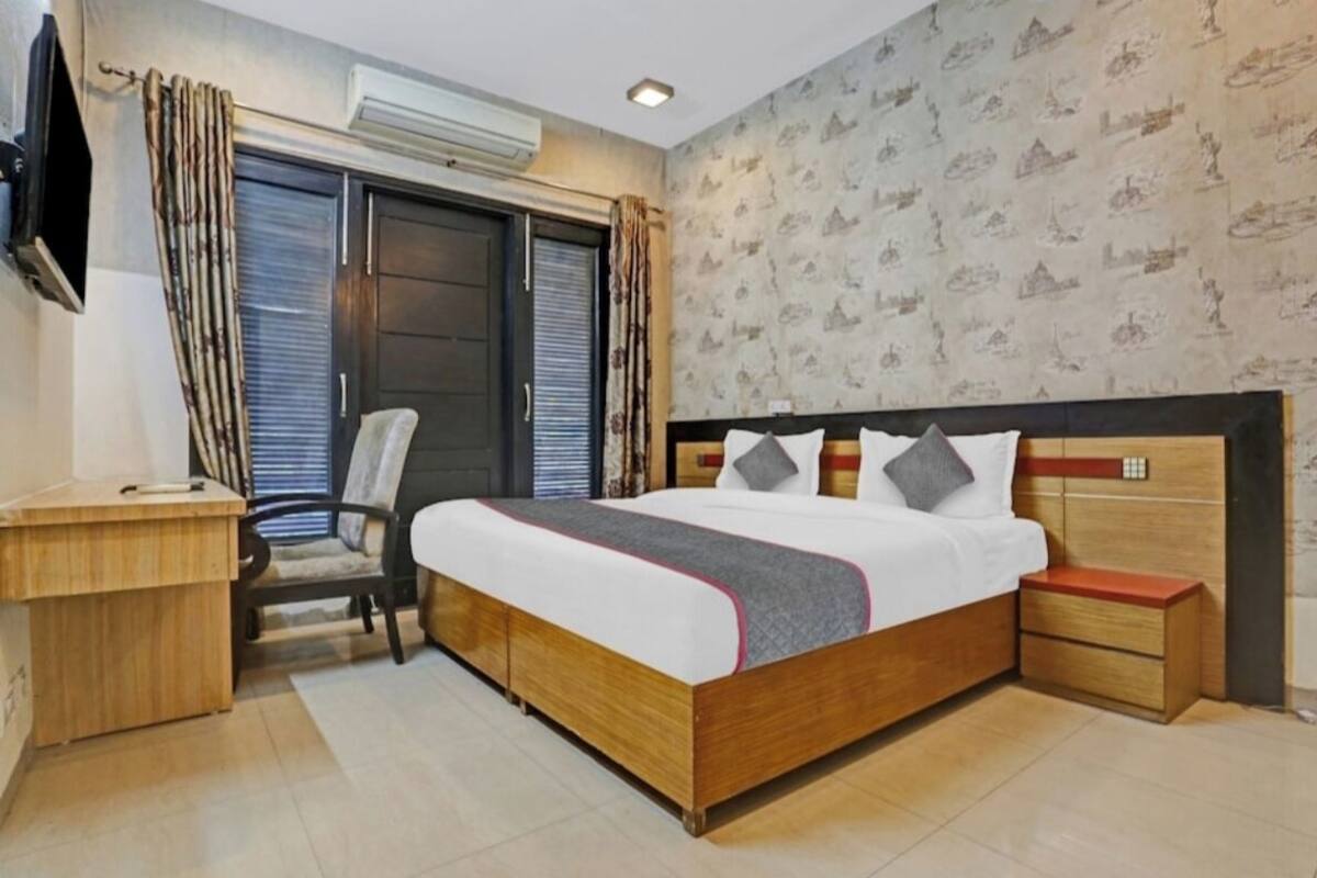 Ein Schlafzimmer mit einem Holzbett, einem Schreibtisch, einem Stuhl und einem an der Wand befestigten Fernseher.
