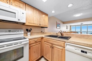 A kitchen with wooden cabinets, a microwave, stove, sink, and dishwasher.