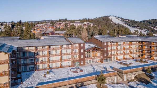 Un hotel de varios pisos con una pista de esquí al fondo.