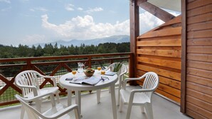 Un balcon avec une balustrade en bois, une table ronde avec des chaises et une vue sur les montagnes.