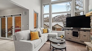 A modern living room with a grey sectional sofa, a coffee table, and a TV on a wooden cabinet. - High Expectations! AC, Community Pool and Spa, Close to Base, New Furnishings! (Steamboat Springs)