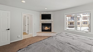 A bedroom with a fireplace, a large window, and a door leading to another room. - High Expectations! AC, Community Pool and Spa, Close to Base, New Furnishings! (Steamboat Springs)