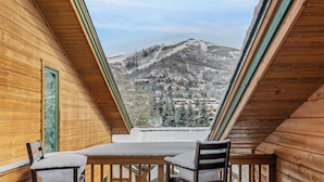 A wooden cabin with a sloped roof and a view of a snow-covered mountain and village. - High Expectations! AC, Community Pool and Spa, Close to Base, New Furnishings! (Steamboat Springs)