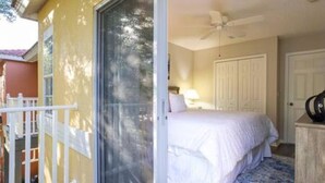 A bedroom with a bed, a ceiling fan, and a door leading to another room.