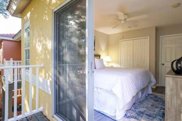A bedroom with a bed, a ceiling fan, and a door leading to another room.