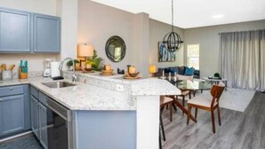 A modern kitchen with a granite countertop, built-in cabinets, and a dining area with a table and chairs.
