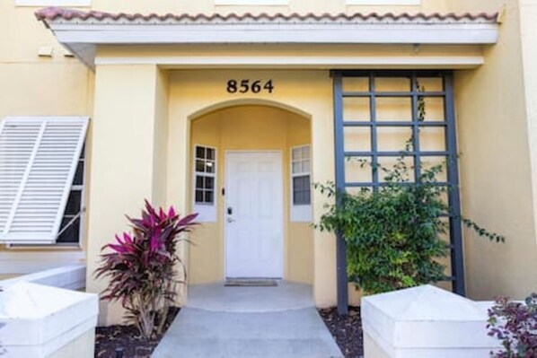 A building with a yellow facade, a white door, and the number 8564 above it.