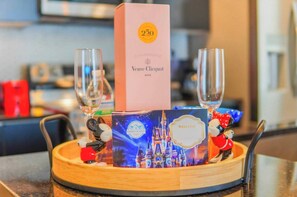 A tray with a champagne box, two glasses, a welcome card, and a Mickey Mouse figurine.