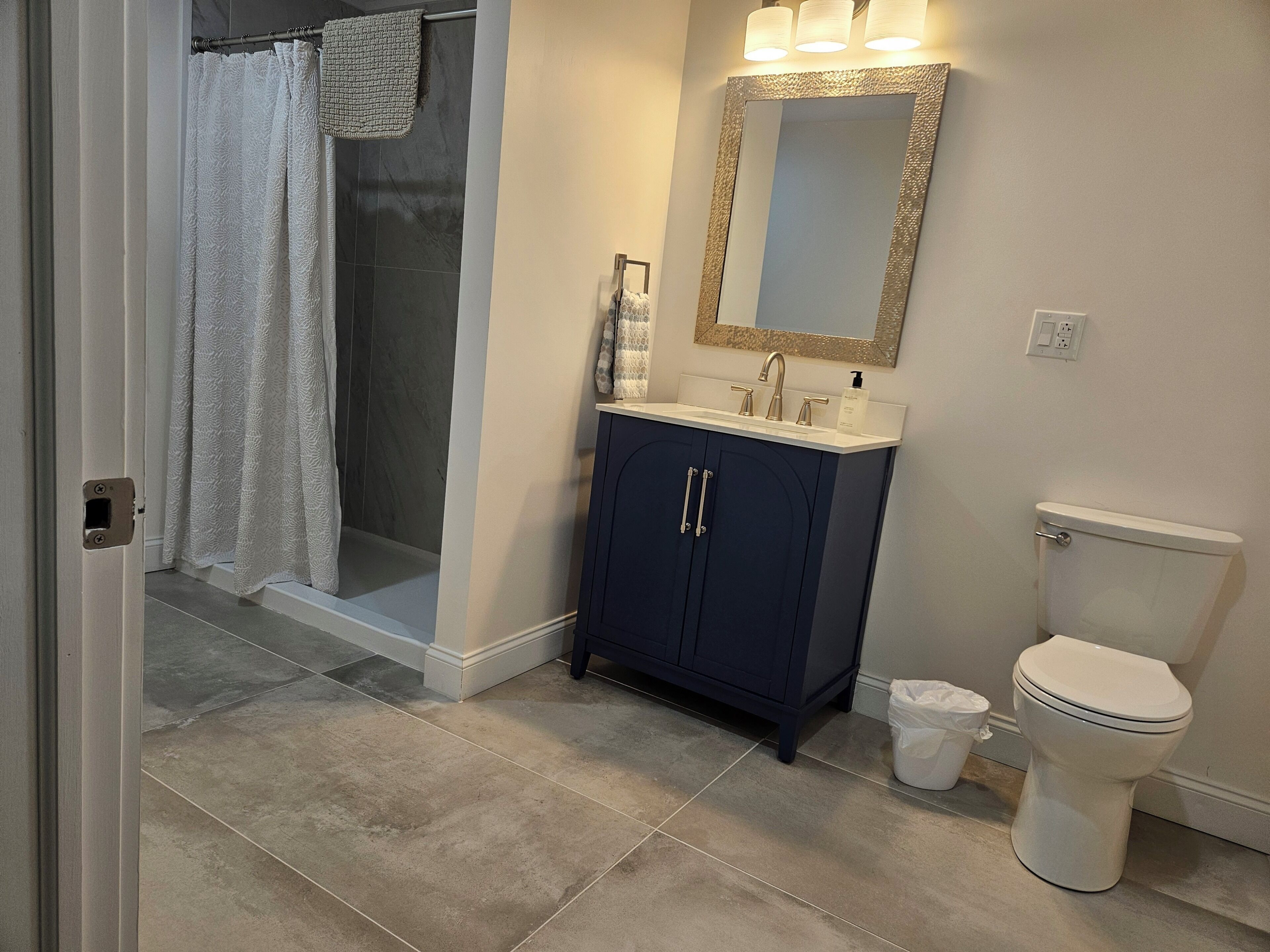 A bathroom with a shower, a sink with a mirror, and a toilet.