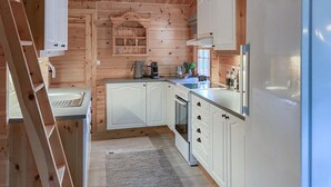 A compact kitchen with white cabinets, a built-in oven, and a refrigerator. - Lovely home in Bjorli with WiFi (Bjorli)