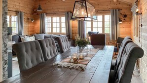 A wooden interior with a long dining table, cushioned seating, and a hanging light fixture. - Lovely home in Bjorli with WiFi (Bjorli)