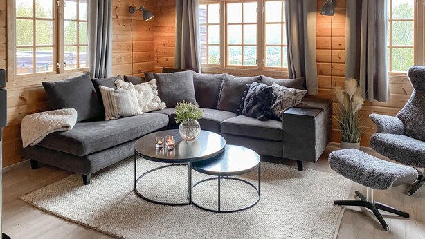 A cozy living room with a grey sectional sofa, a round coffee table, and a patterned armchair. - Lovely home in Bjorli with WiFi (Bjorli)