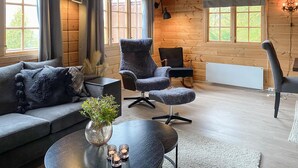 A cozy living room with a grey sofa, a matching armchair, a small round table with a vase and candles, and a dining area with a table and chairs. - Lovely home in Bjorli with WiFi (Bjorli)