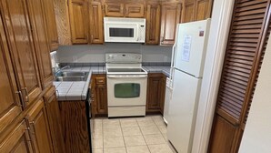 A kitchen with wooden cabinets, a microwave, stove, and refrigerator.