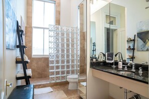 A bathroom with a glass shower enclosure, a toilet, a sink with a mirror, and a towel rack.