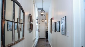 A hallway with mirrored walls, a hanging light fixture, and framed pictures.
