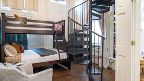 A bunk bed with a ladder, a chair, a spiral staircase, and a door. - Engine 24 Firehouse Room 3 (New Orleans)