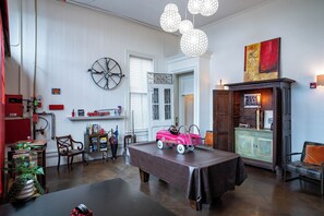 Quarto com mesa de jantar, cadeiras, um brinquedo de bombeiros, um objeto decorativo em forma de roda e um armário com luminária.
