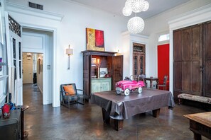 Une pièce avec une table en bois, une chaise, une lampe et une porte rouge.