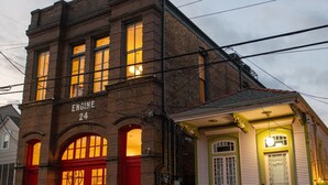 A brick building with a sign reading "ENGINE 24" and a small attached structure with a green door. - Engine 24 Firehouse Penthouse Suite (New Orleans)