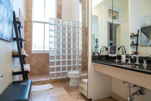 A bathroom with a glass shower enclosure, a black vanity with a mirror, and a toilet.