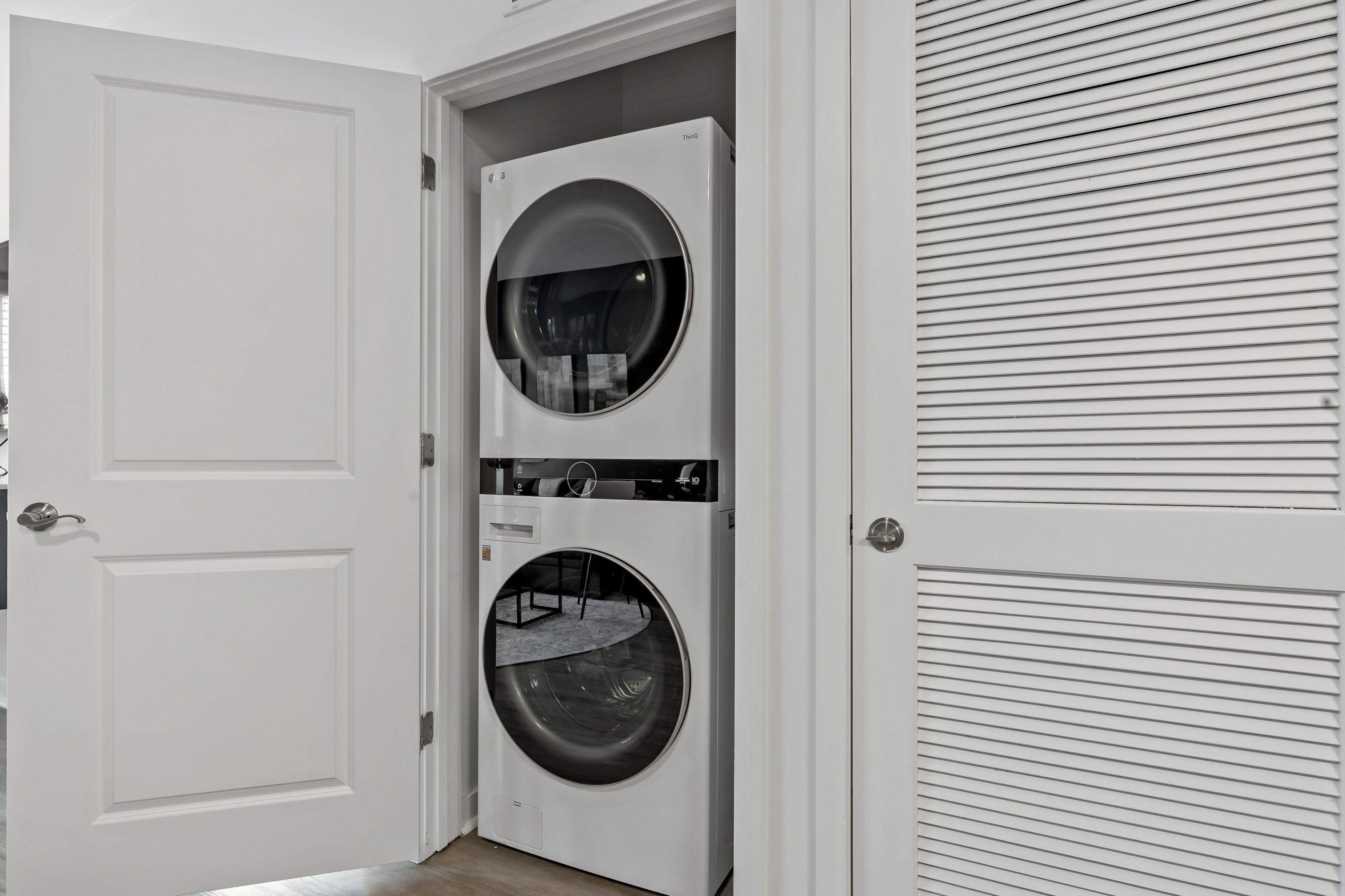 A laundry room with two stacked front-loading washing machines and a closed door.