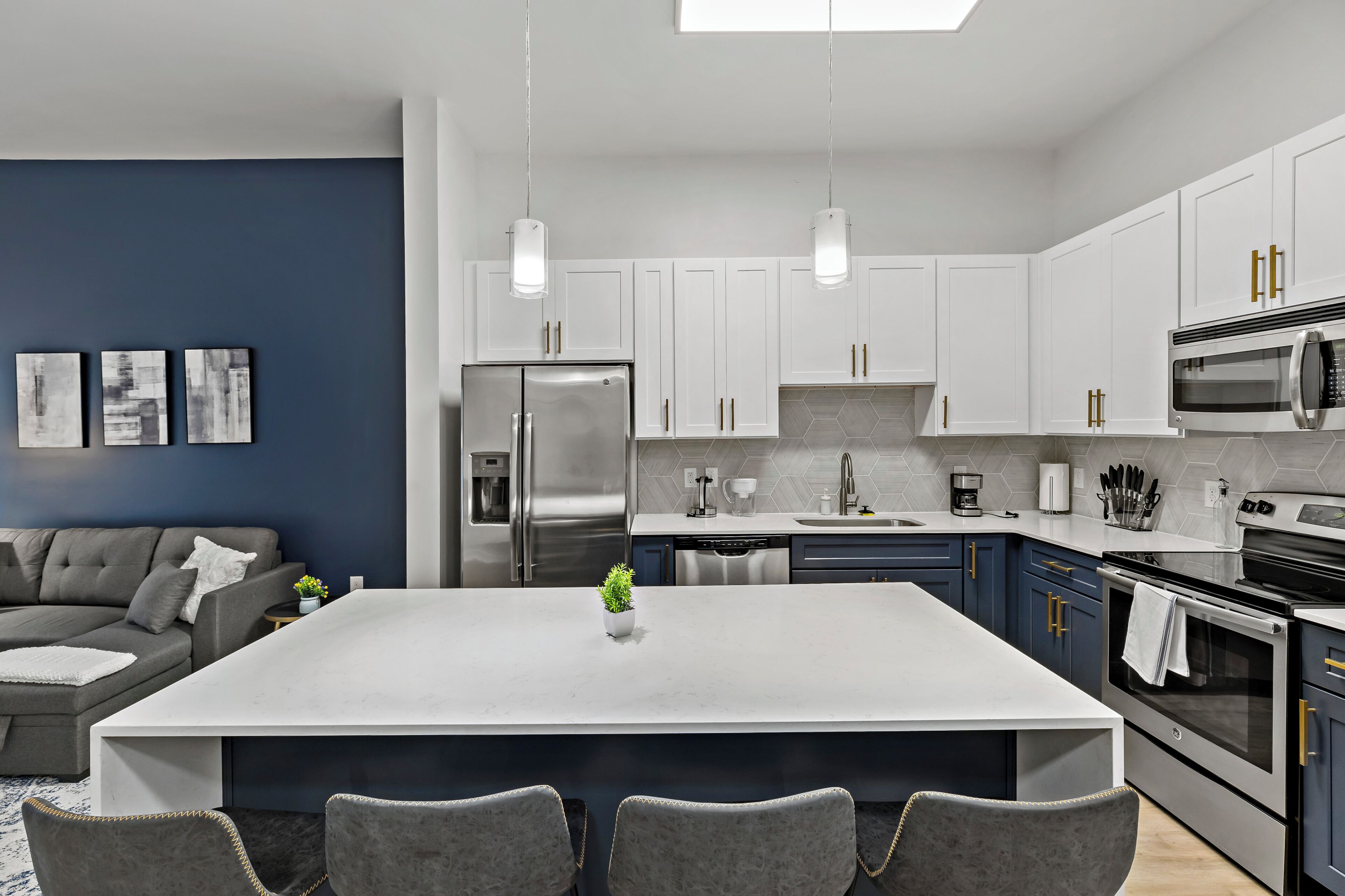 A modern kitchen with white cabinets, stainless steel appliances, and a central island.