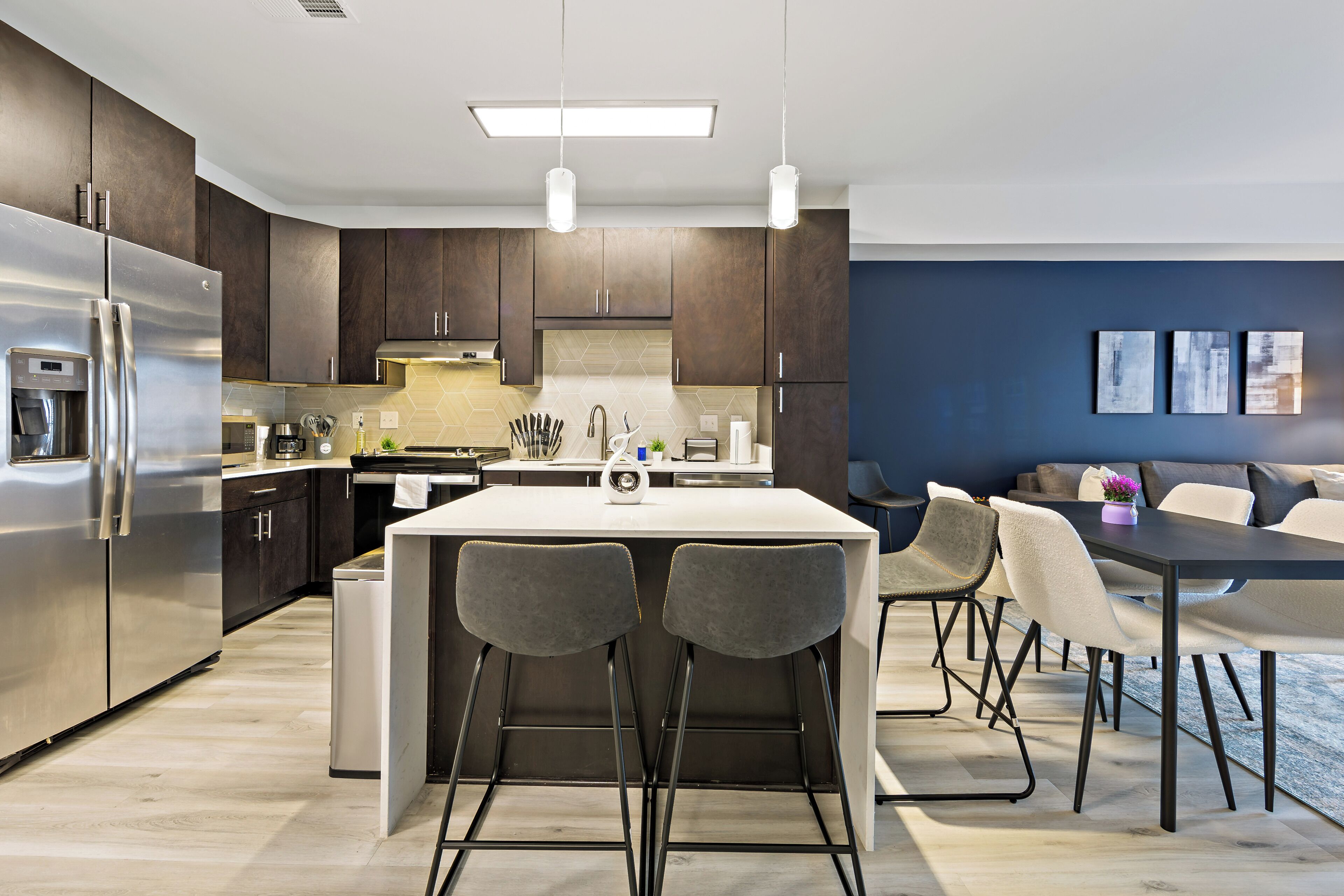 A modern kitchen with dark wood cabinets, stainless steel appliances, and a central island with bar stools.