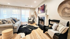 Un salon moderne avec un canapé, un lit à cadre noir, une cheminée et une grande tapisserie murale tissée.
