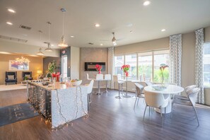 Una cocina moderna con una isla central, comedor con mesa y sillas redondas, y sala de estar con sofá y televisor.
