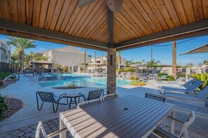 A poolside area with wooden deck, lounge chairs, and a table. - ROVE LIVING/KB - Merino (Scottsdale)
