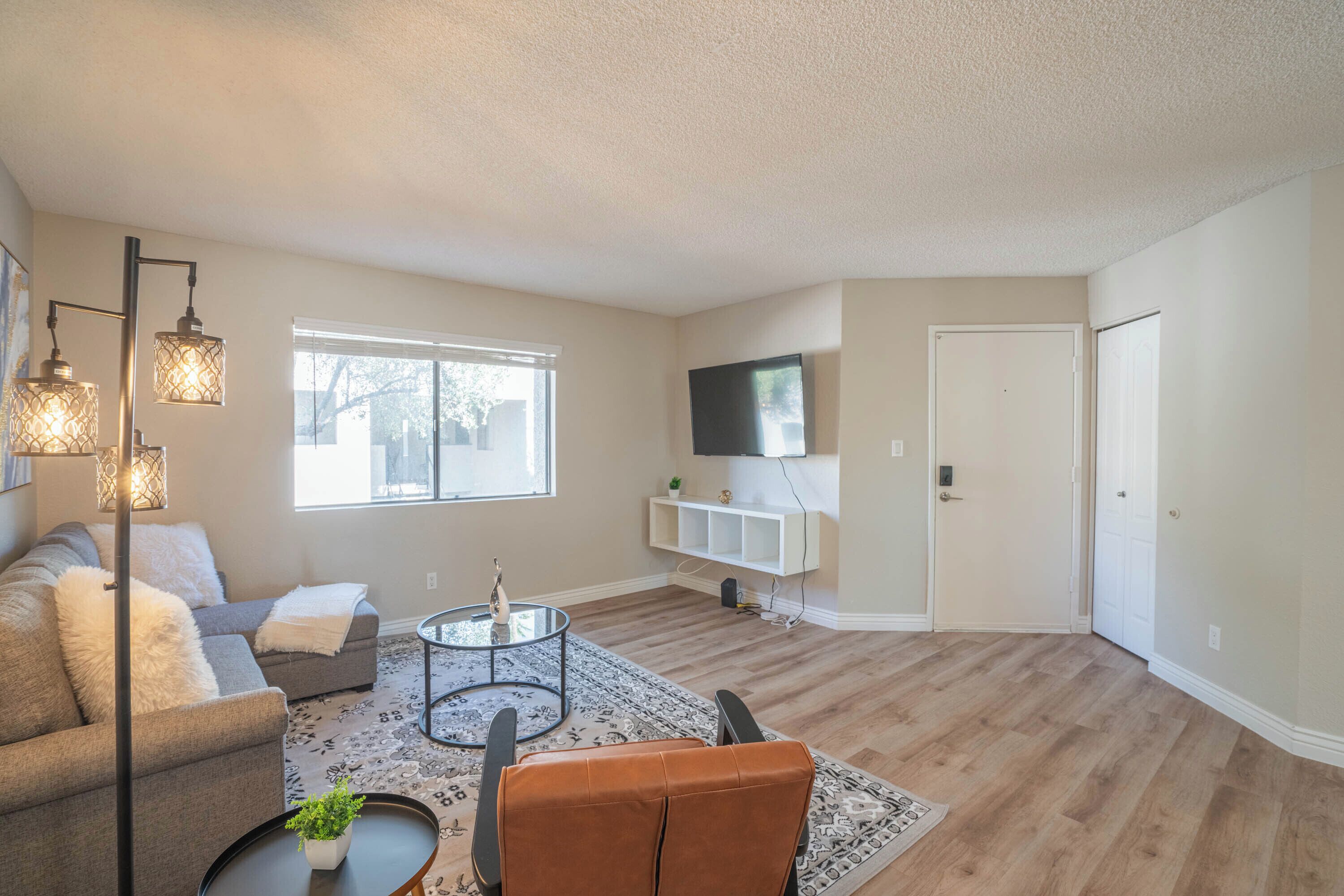 A living room with a sectional sofa, a coffee table, and a TV mounted on the wall.