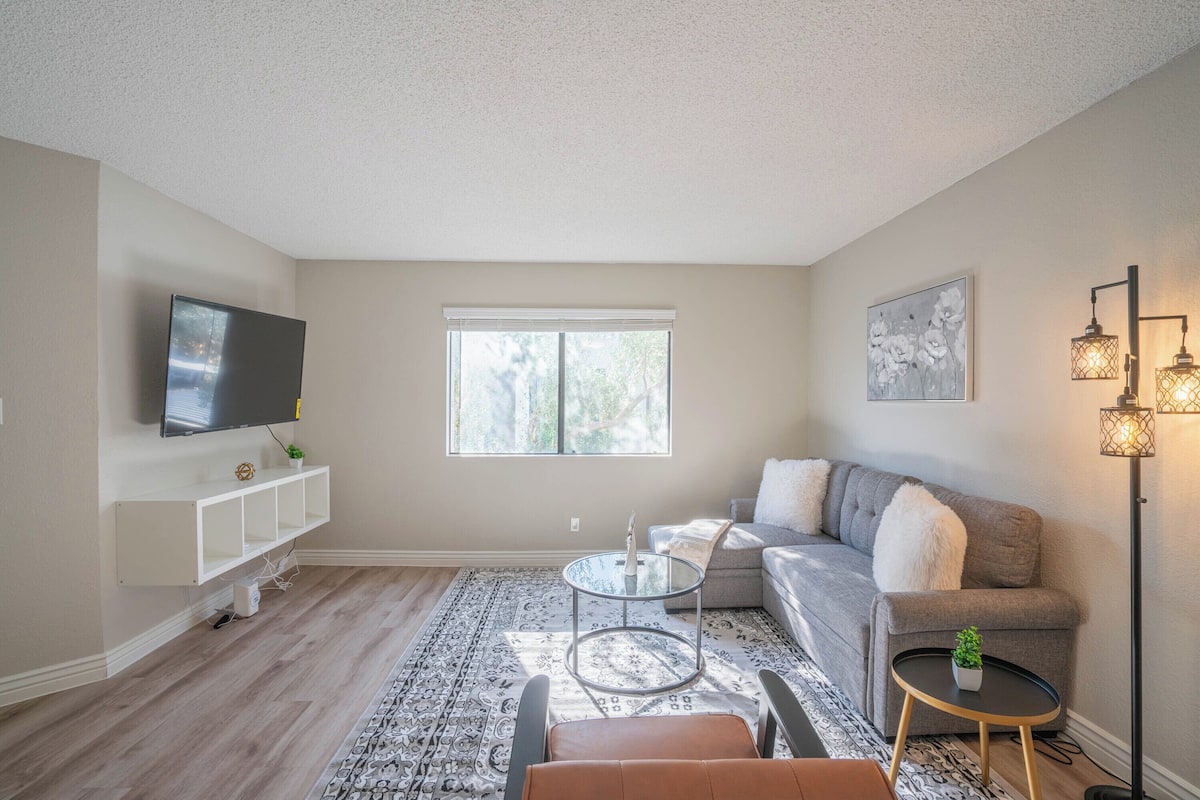 A living room with a TV, sofa, coffee table, and floor lamp.