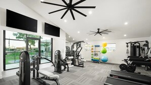 A modern gym with exercise equipment, large windows, and a view of the outdoors.