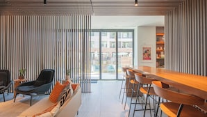 Un interior moderno con un sofá, sillones, una barra de madera y vistas al exterior.