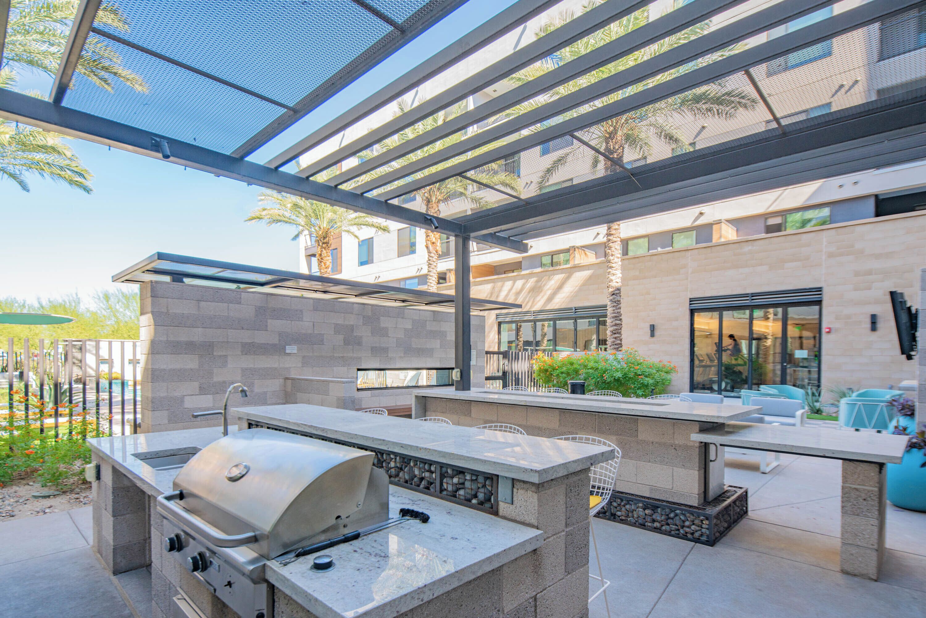 Un patio al aire libre con una parrilla, una zona de estar y vistas del edificio al fondo.