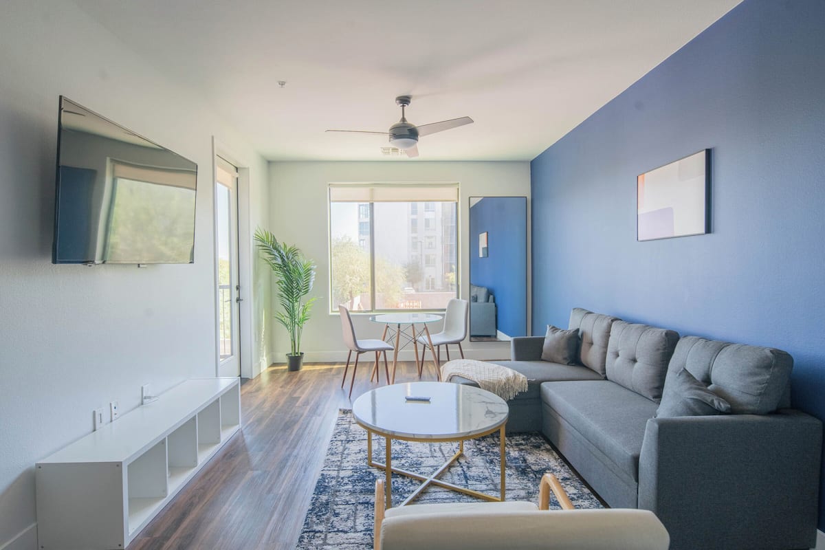 A modern living room with a sofa, a coffee table, a TV, and a ceiling fan.