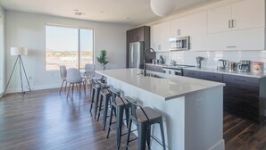 Una cocina moderna con una isla grande, taburetes de bar y vistas al desierto.