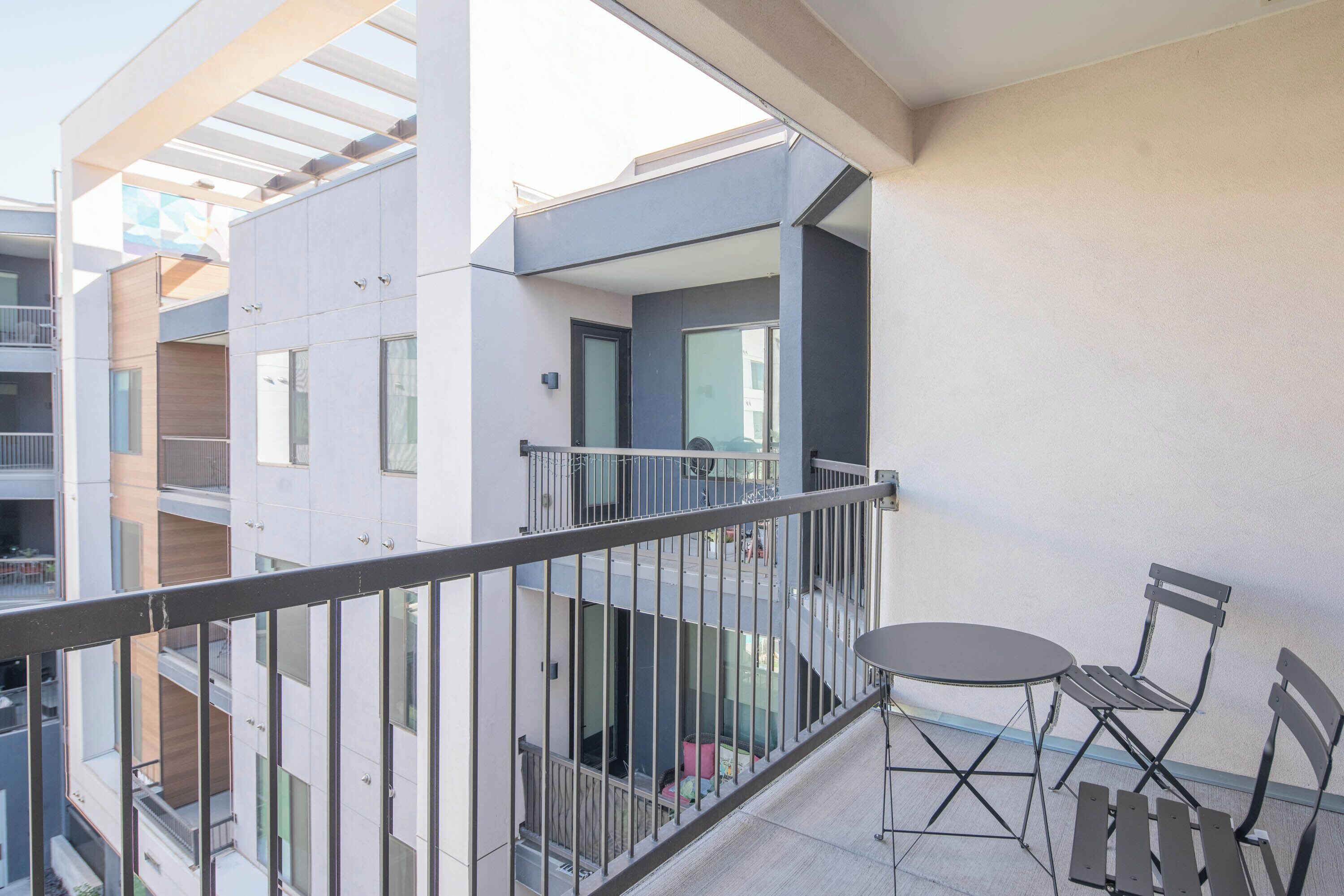 A balcony with a metal railing, a small table, and two chairs.