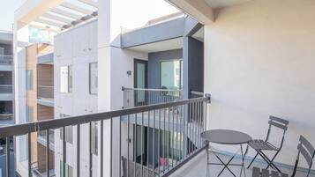 A balcony with a metal railing, a small table, and two chairs.